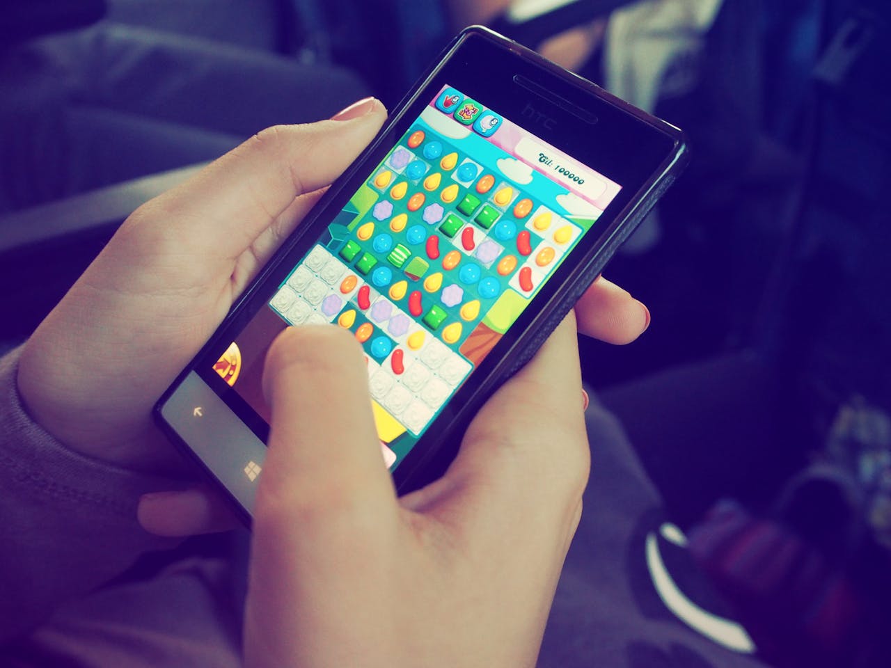 Services-02 Hands holding a smartphone with a colorful puzzle game on the screen, displaying modern technology.